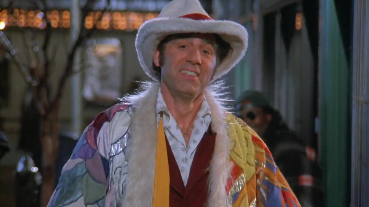Kramer steps out wearing the technicolor dreamcoat and a lady